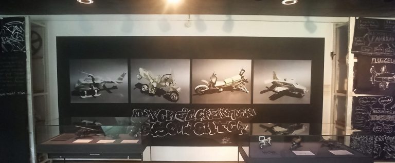 Ausstellungswand mit großformatigen Objektfotos und Kreidezeichnungen der Jugendlichen