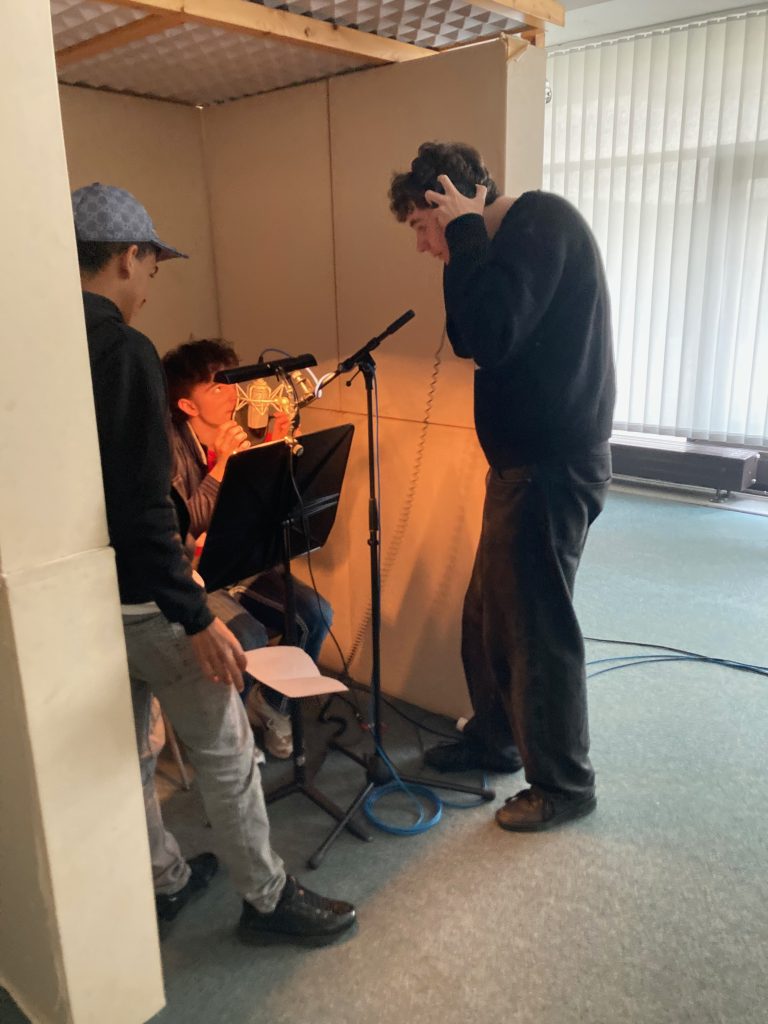 Drei Jugendliche bei der Aufnahme im Tonstudio